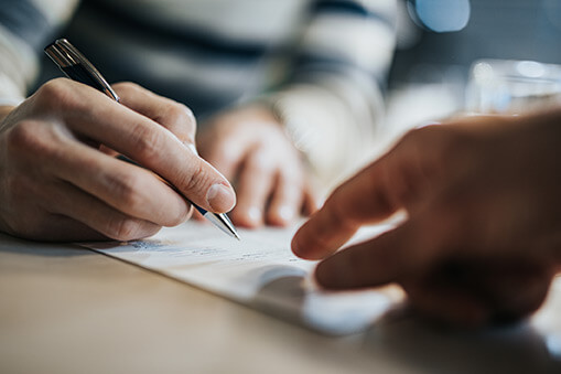 Man signing a contract while advisor is aiming at the place he need to sign.